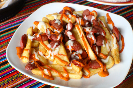 Salchipapas - Thinly sliced pan-fried beef hot dogs and French fries mixed together. The dish is served with a dipping sauce.
